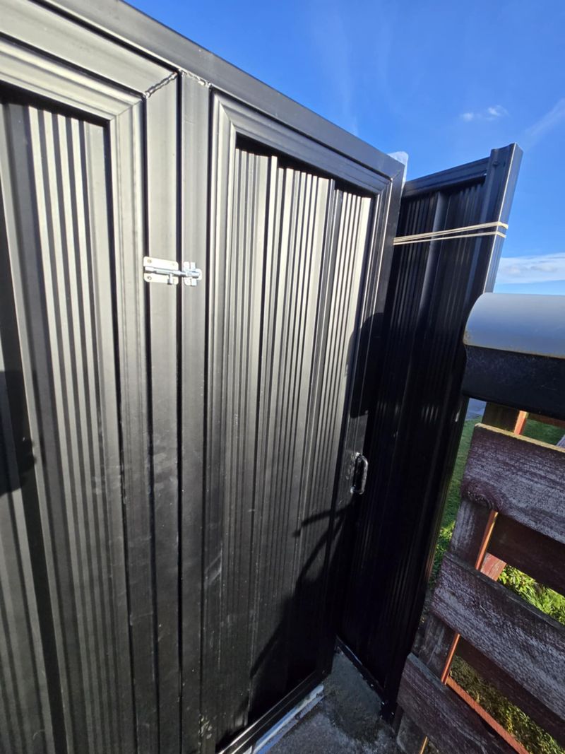 Black privacy gate with vertical slats and latch